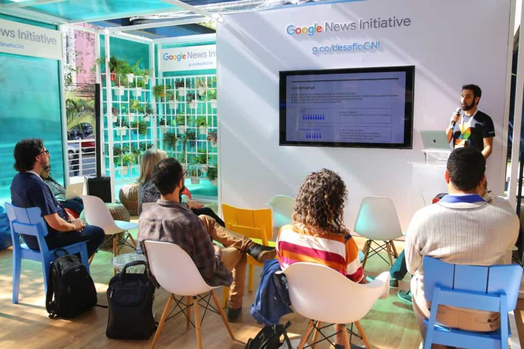 Apresentação do Prisma Conteúdo na feira de tecnologia com público assistindo a palestra.