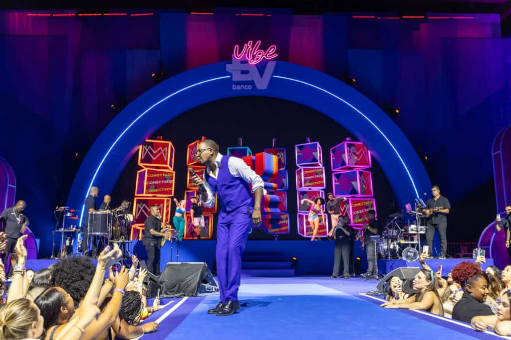 Performers ao vivo com banda e cantor em show vibrante no palco do evento.